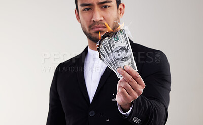 Buy stock photo Studio shot of a young businessman burning a banknote against a white background