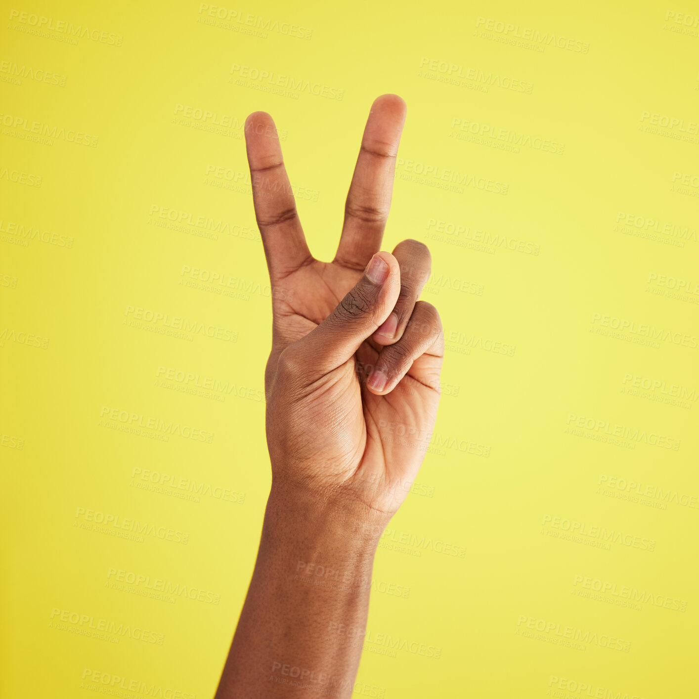 Buy stock photo Studio shot of an unrecognisable man making a peace sign against a yellow background