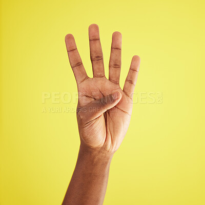 Buy stock photo Studio shot of an unrecognisable man showing four fingers against a yellow background