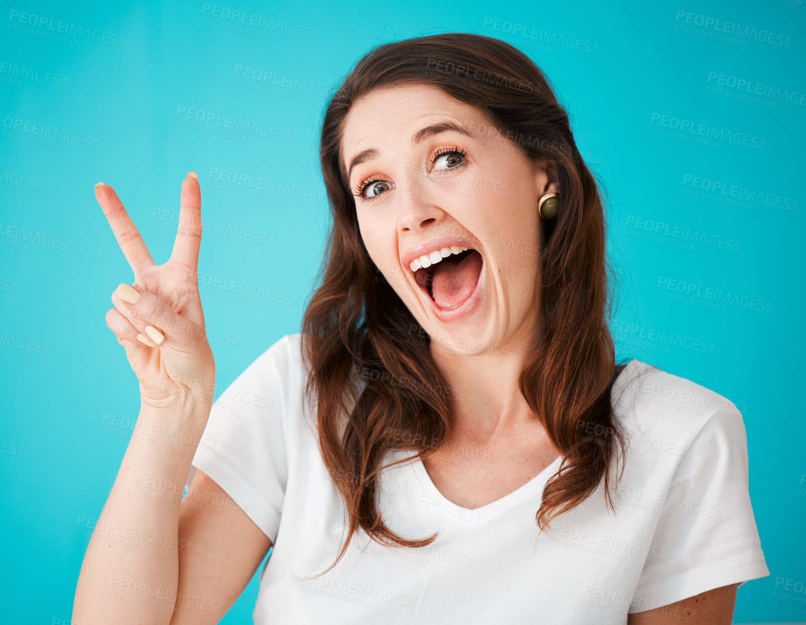 Buy stock photo Excited, woman and portrait with peace sign in studio for support, positivity and kindness. Happy, female person and hand with v emoji gesture for feedback, care and unity on blue background