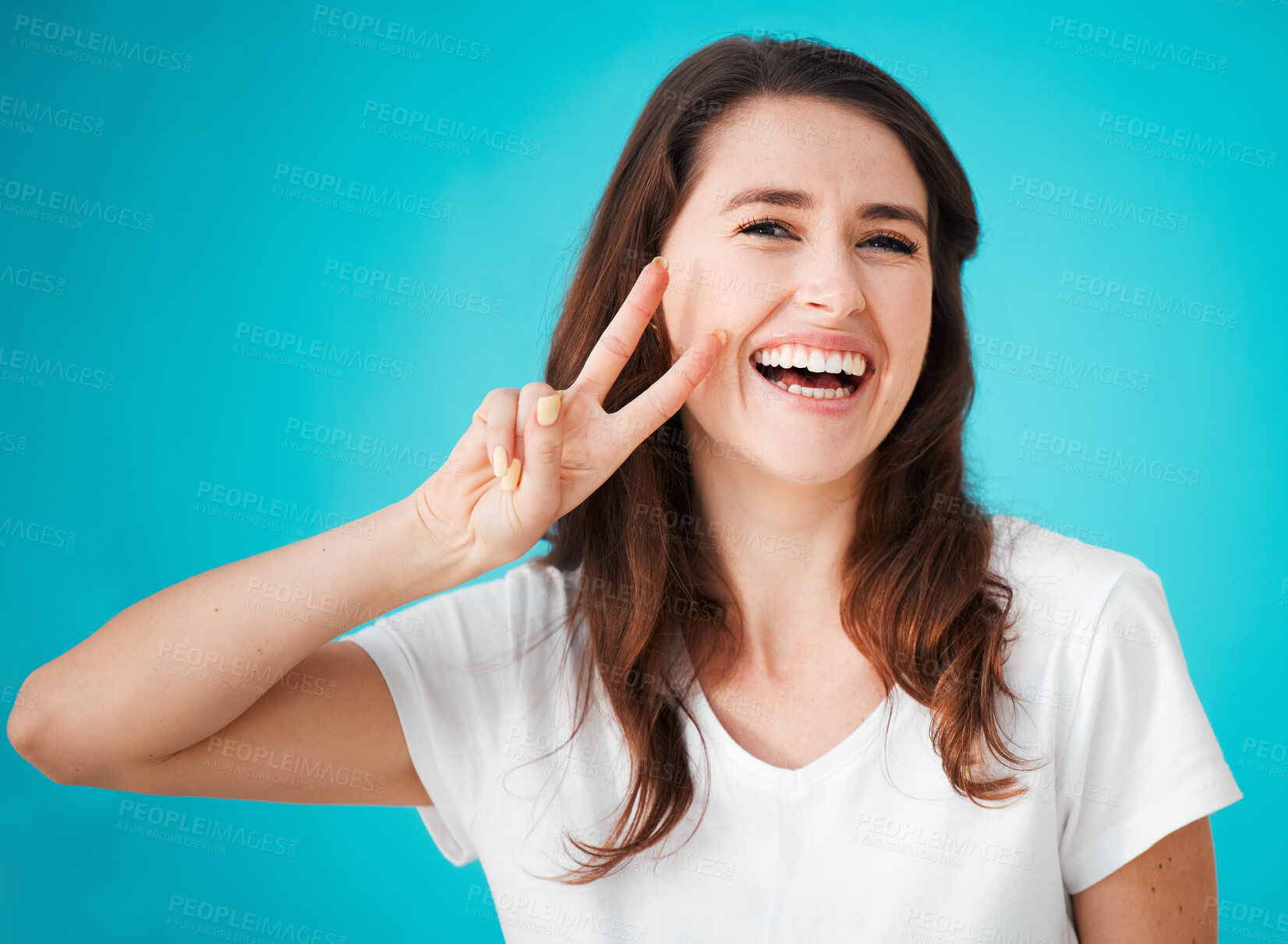 Buy stock photo Woman, smile and portrait with peace sign in studio for support, positivity and kindness emoji. Confident, female person and happy with v gesture for feedback, unity and care on blue background