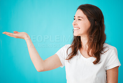 Buy stock photo Studio shot of an attractive young woman posing with her hand out against a blue background