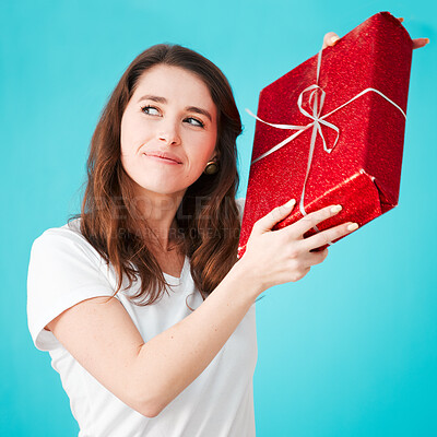 Buy stock photo Woman, studio and thinking with gift in box or package with smile, thoughts and guess on blue background. Female person, happy and satisfied with Christmas present as giveaway product and prize