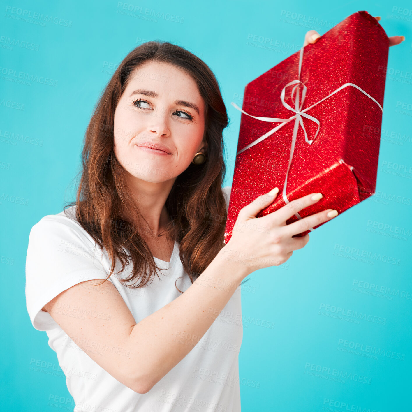 Buy stock photo Woman, studio and thinking with gift in box or package with smile, thoughts and guess on blue background. Female person, happy and satisfied with Christmas present as giveaway product and prize