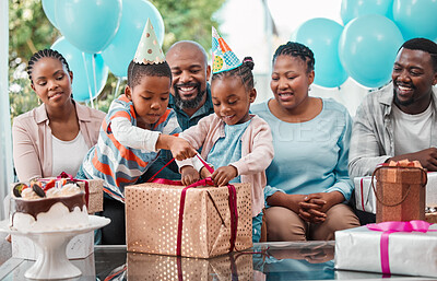 Buy stock photo Shot of two siblings opening a gift together at a birthday party
