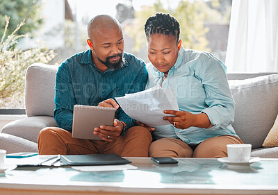 Buy stock photo Shot of a mature couple looking through their bills while using a digital tablet