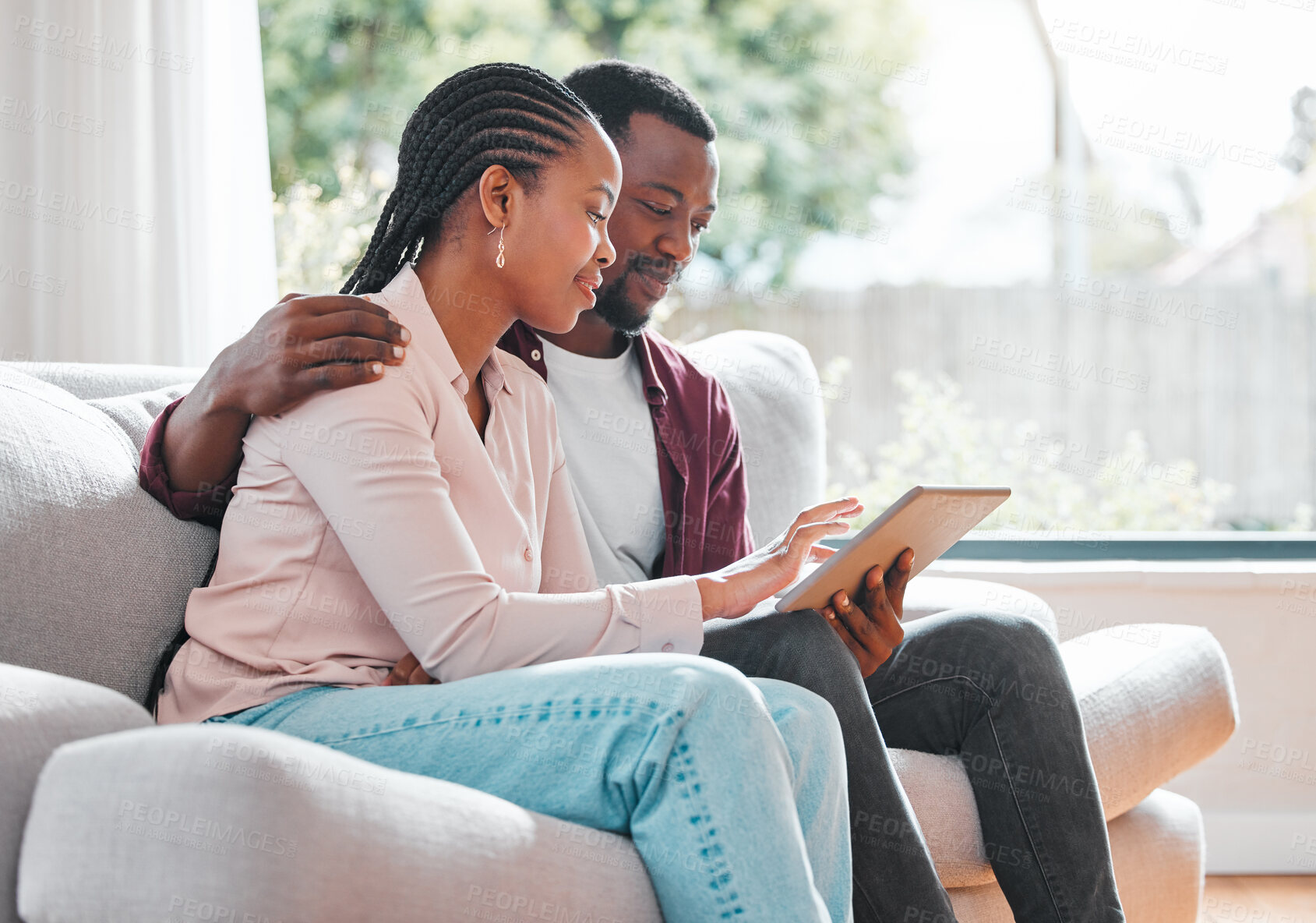 Buy stock photo Shot of a young couple relaxing at home using a digital tablet