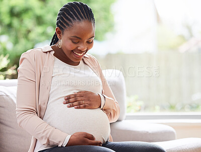 Buy stock photo Cropped shot of an attractive young mother to be sitting on the sofa at home