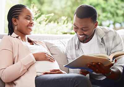 Buy stock photo Cropped shot of a handsome young man reading a book to pregnant wife's belly while sitting on the sofa at home