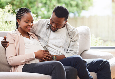 Buy stock photo Black couple, pregnancy and hand on stomach for love, support and feeling baby kick in home. Future parents, hug and touch belly in living room for growth, maternity and commitment in relationship