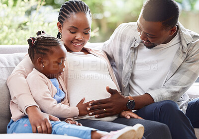 Buy stock photo Cropped shot of an attractive young pregnant woman sitting on the sofa at home with her husband and daughter