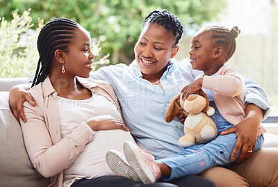 Buy stock photo Cropped shot of an attractive young pregnant woman sitting on the sofa at home with her mother and daughter