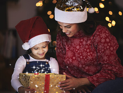 Buy stock photo Shot of a young mother and daughter opening up a Christmas gift at home
