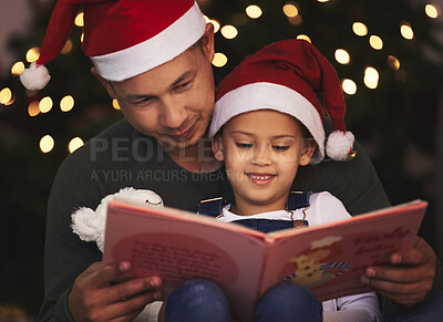 Buy stock photo Shot of a young father and daughter reading a book during Christmas time at home