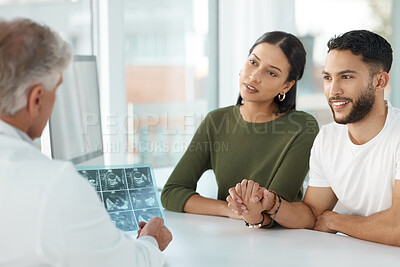 Buy stock photo Shot of a young couple sitting with their obstetrician and holding hands during a consultation in the clinic
