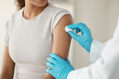 Buy stock photo Cropped shot of an unrecognisable doctor standing and using a cotton swab on her patient's arm before administering an injection