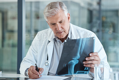 Buy stock photo Shot of a male doctor reviewing a patient's x-ray