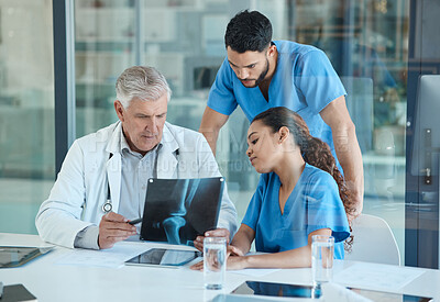 Buy stock photo Shot of a group of medical staff reviewing a patients x-ray