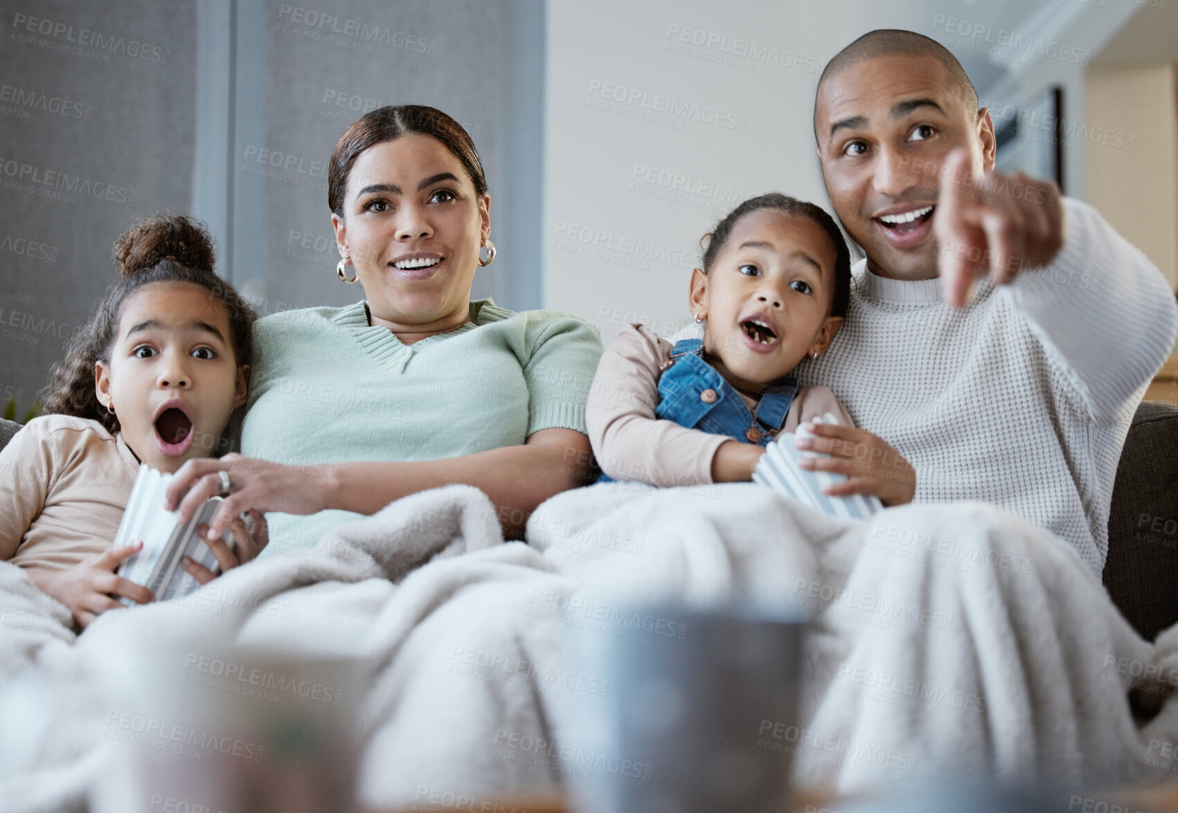 Buy stock photo Shot of a happy family eating popcorn while watching television together at home