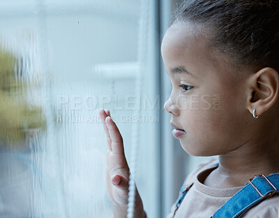 Buy stock photo Shot of a little girl starting out of the window looking sad at home