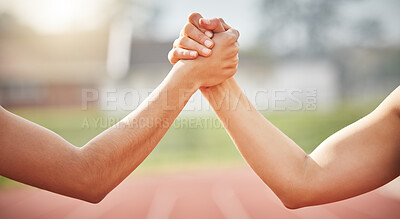 Buy stock photo Cropped shot of two unrecognizable female athletes shaking hands in solidarity while standing out on track