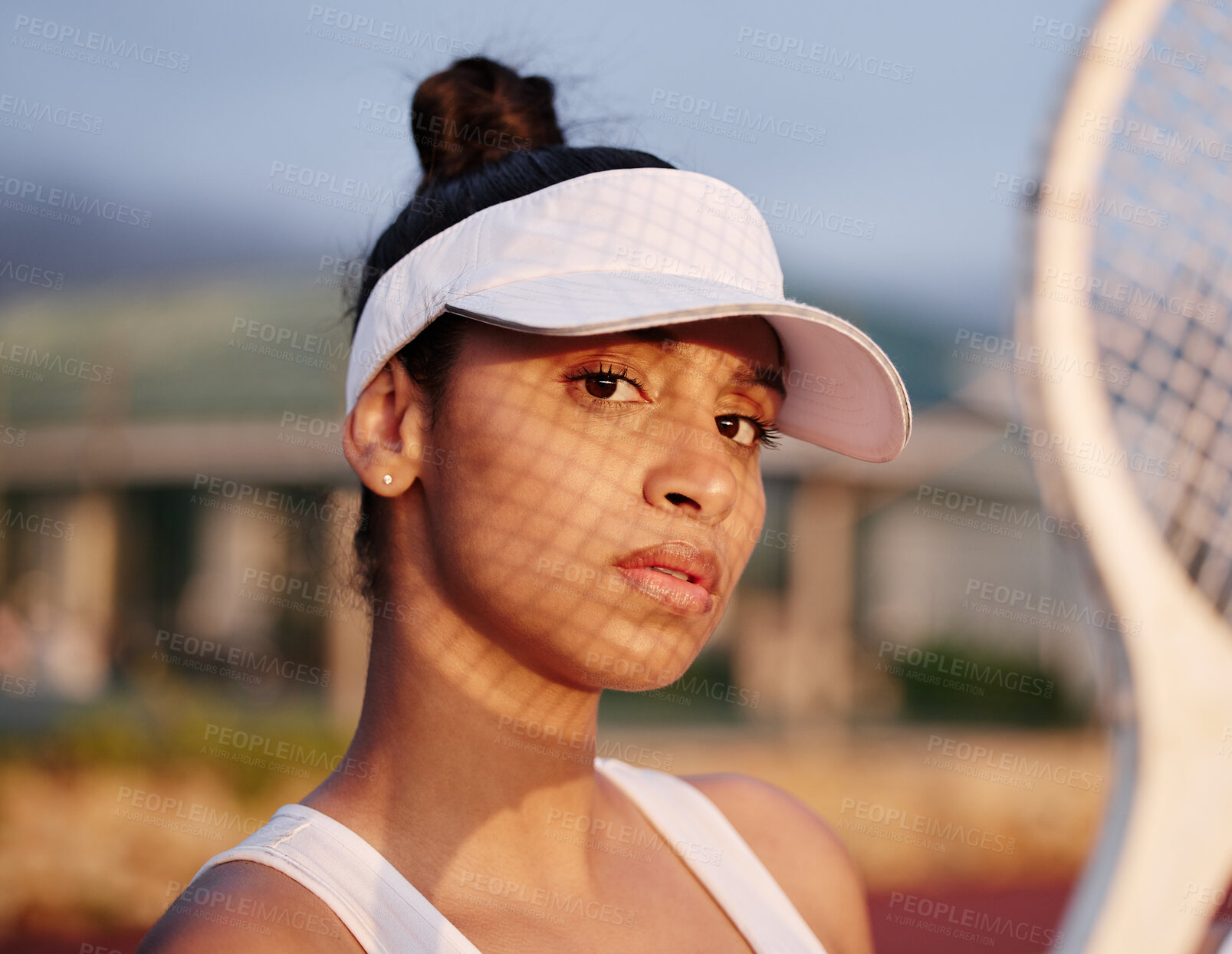 Buy stock photo Shot of a sporty young woman posing with a tennis racket on a court