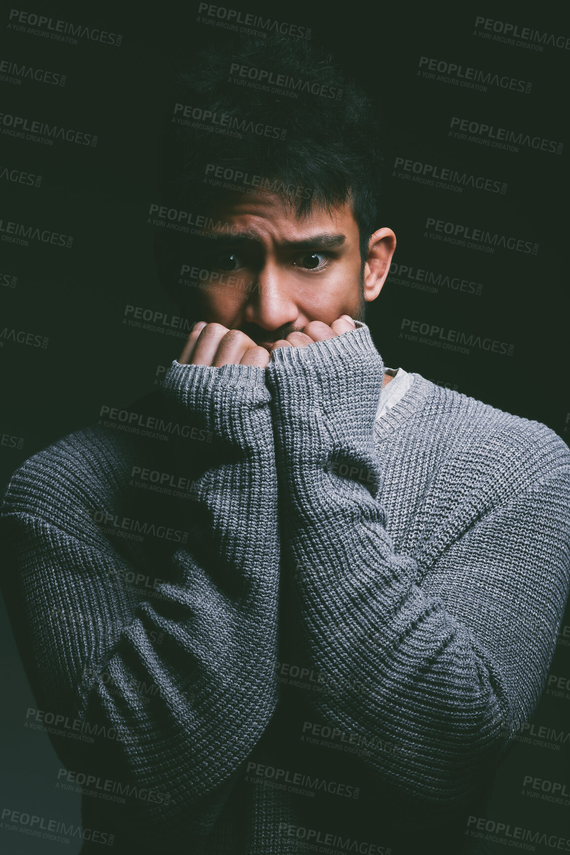 Buy stock photo Shot of a young man looking nervous against a dark background