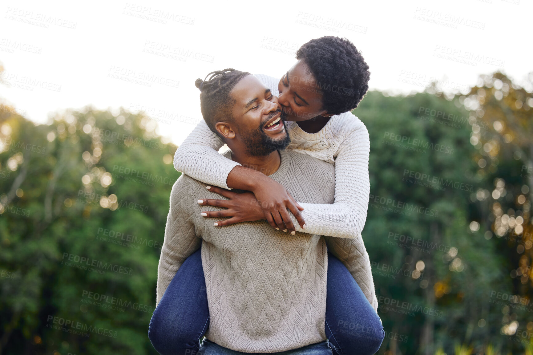 Buy stock photo Piggyback, kiss and happy black couple at park for anniversary date or honeymoon romance with smile. Wellness, hug and African people in nature with support, care and love on holiday fun in garden