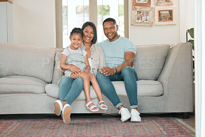 Buy stock photo Full length shot of a young couple sitting on their sofa at home with their daughter