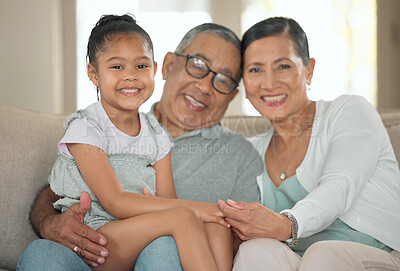 Buy stock photo Shot of a senior couple sitting on their sofa at home with their granddaughter