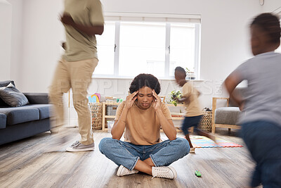 Buy stock photo Shot of a young woman looking stressed out while her family run around her at home