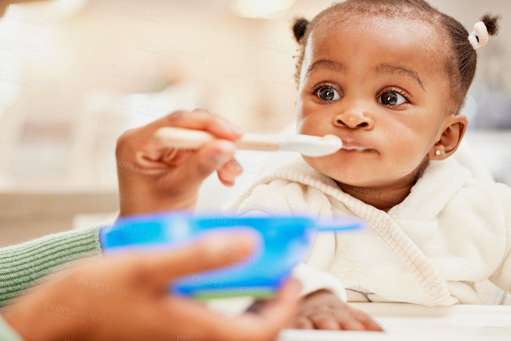 Buy stock photo Cropped shot of an adorable little girl being fed by her mother in the kitchen at home