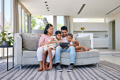 Buy stock photo Shot of a young family relaxing together while using a digital tablet