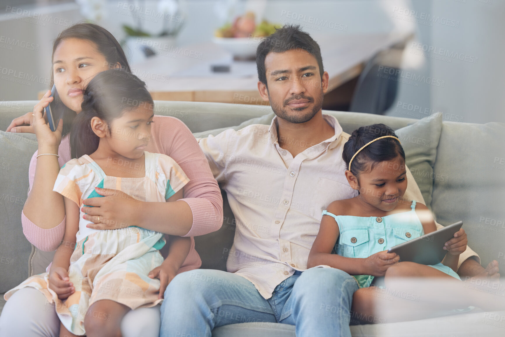 Buy stock photo Technology, parents and kids on sofa with busy family, internet and relax together in home. Mom, dad and girl children on couch watching tv with phone, tablet and online connectivity in living room.