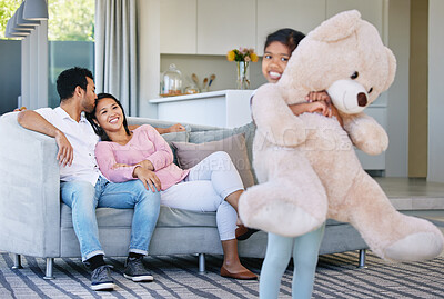 Buy stock photo Shot of a little girl holding her teddy bear while her parents look on