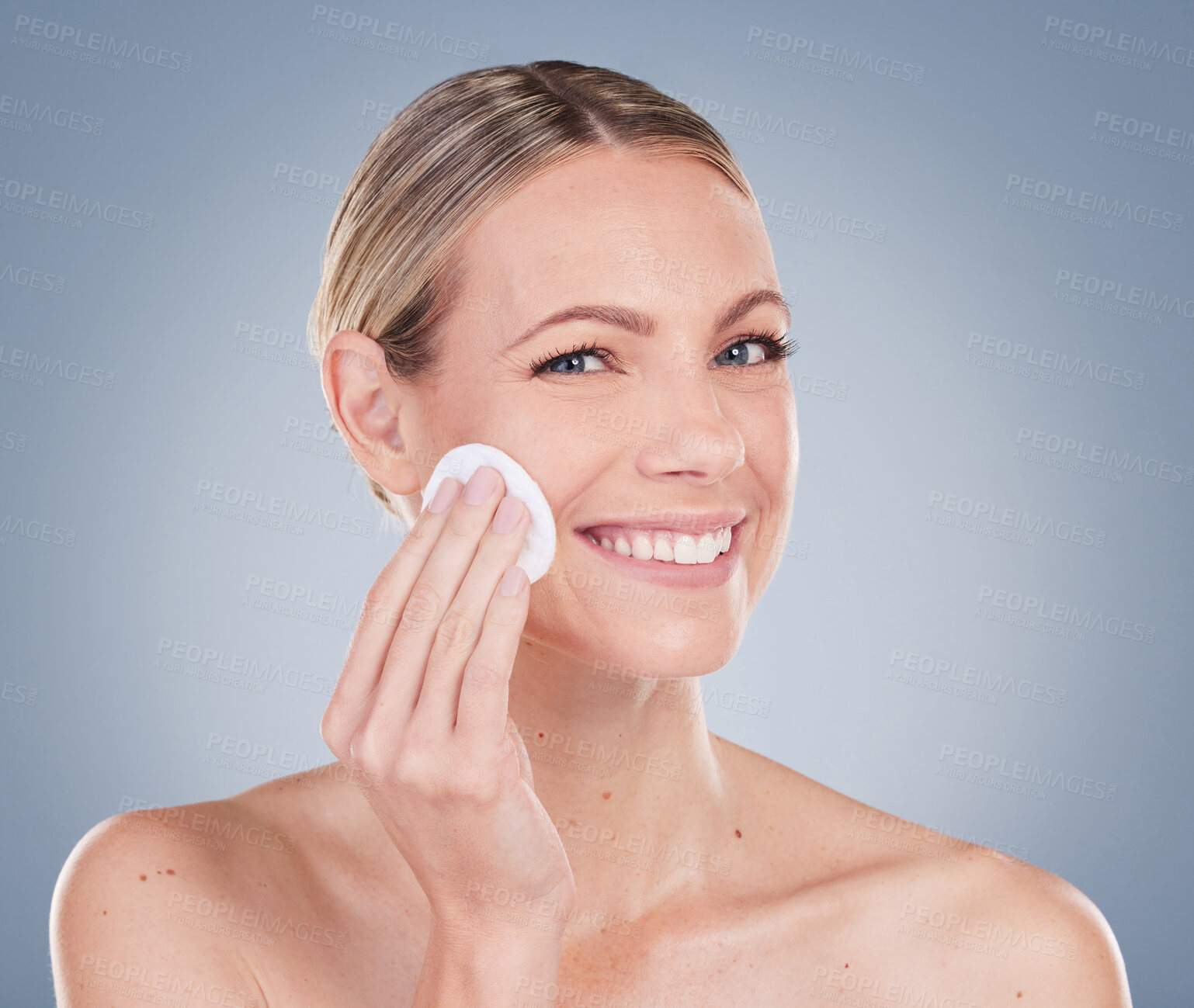 Buy stock photo Studio portrait of an attractive young woman exfoliating her face against a grey background