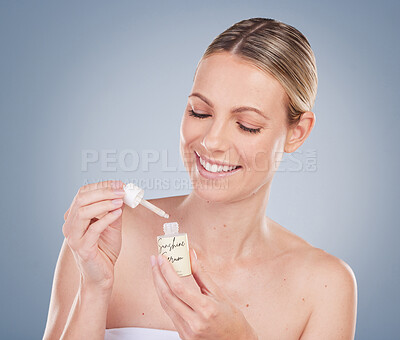 Buy stock photo Studio shot of an attractive young woman applying facial serum against a grey background