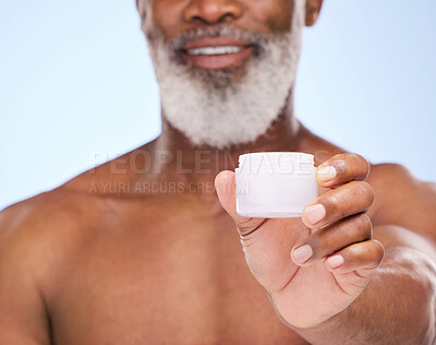 Buy stock photo Cropped shot of a mature man holding face moisturiser in his hand against a blue background