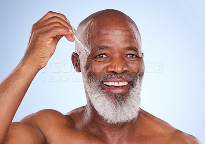 Buy stock photo Studio portrait of a mature man applying serum to his face against a blue background