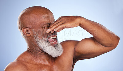 Buy stock photo Studio shot of a mature man holding his nose in disgust against a blue background