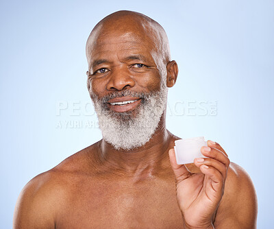 Buy stock photo Studio portrait of a mature man holding face moisturiser in his hand against a blue background