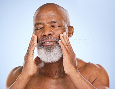Buy stock photo Studio shot of a mature man applying moisturiser to his face against a blue background
