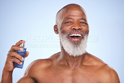 Buy stock photo Studio portrait of a mature man spraying himself with aftershave against a blue background