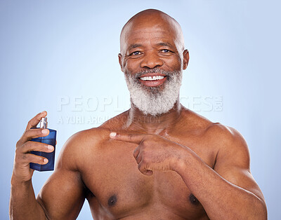 Buy stock photo Black man, perfume and point for beauty in studio, fragrance and smell for hygiene on blue background. Portrait, smile and shirtless for male person, product or cologne for luxury deodorant spray