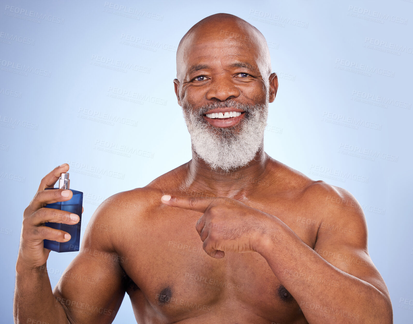 Buy stock photo Black man, perfume and point for beauty in studio, fragrance and smell for hygiene on blue background. Portrait, smile and shirtless for male person, product or cologne for luxury deodorant spray