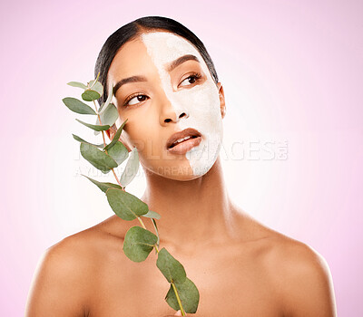 Buy stock photo Studio shot of an attractive young woman holding a  plant and having a facial against a pink background