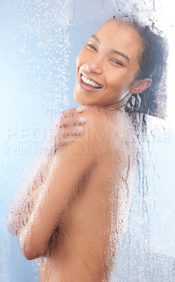 Buy stock photo Studio portrait of an attractive young woman taking a shower against a blue background