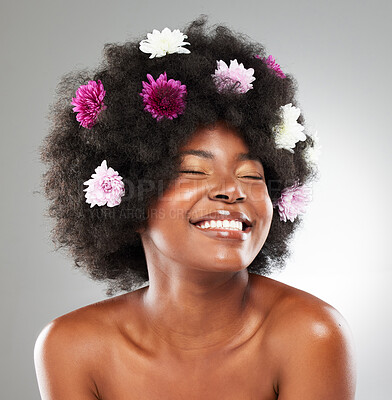 Buy stock photo Black woman, happy and flowers in studio for hair care, natural beauty and skincare with shine or glow. Girl, afro and pink plants with smile for wellness, organic cosmetics and grey background.