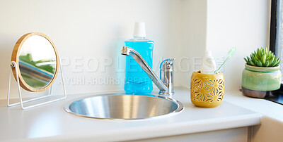 Buy stock photo Shot of a toothbrush and mouthwash in a container at home in the bathroom