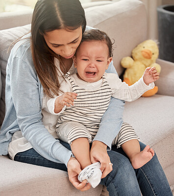 Buy stock photo Baby, crying and mom with socks in home for girl feet, cold weather and keep warm in winter. Female child, mother and relax on sofa in living room for dress kid, sad and unhappy for barefoot